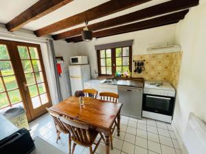 a kitchen with a wooden table and chairs and a kitchen with a sink at Le Moulin L'Eveque in Campeaux