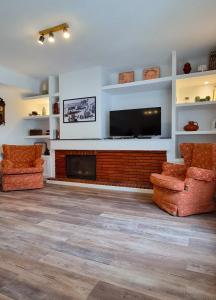 a living room with two chairs and a fireplace at Las raíces de los abuelos in Guadalix de la Sierra