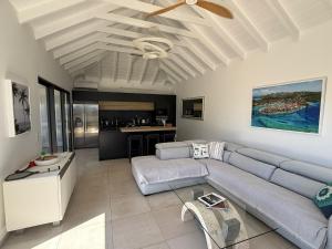 a living room with a couch and a ceiling fan at Spacious Modern Villa with Pool & Sunrise View - Graviola St Barth in Marigot