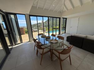 a living room with a glass table and chairs at Spacious Modern Villa with Pool & Sunrise View - Graviola St Barth in Marigot