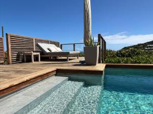 a swimming pool next to a deck with a chair and a bench at Spacious Modern Villa with Pool & Sunrise View - Graviola St Barth in Marigot