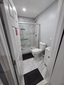 a white bathroom with a shower and a toilet at Newly built Studio Close to NYC and EWR in Irvington