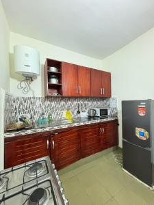 a kitchen with wooden cabinets and a black refrigerator at Synacassi 2 in Abidjan
