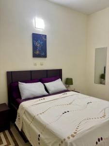a bedroom with a large bed with a purple headboard at Synacassi 2 in Abidjan