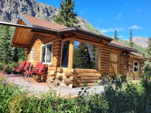 a log cabin with red chairs on a deck at Little Bear Getaway Cabins in Glacier View