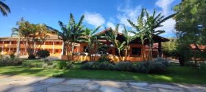 a house with palm trees in front of it at Fazenda Pousada Cachoeira do Flávio in São Thomé das Letras