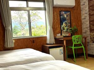 a bedroom with a bed and a desk and a green chair at 十畝田山莊 in Chishang