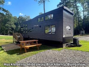 a black tiny house with a picnic table and a bench at Huckleberry Hideaway in Minden