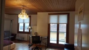 a living room with a chandelier and two windows at room for rent in Bolligen