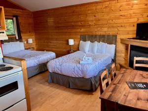 a room with two beds and a table and a stove at Bear Cove Cottages in Port Hardy
