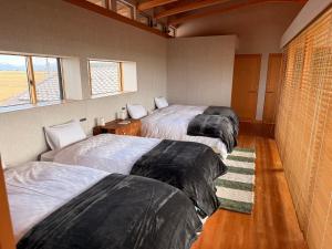 two beds in a room with two windows at the Mikuni Residence in Sakai
