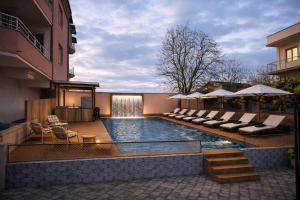 a swimming pool with chairs and umbrellas next to a building at Villa & Apartments Antigona in Ohrid