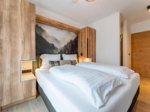 a bedroom with a large white bed with a painting on the wall at Grebenzen Lodge 44 in Sankt Lambrecht