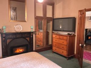 a bedroom with a fireplace and a television on a dresser at Bromwich Guest House - 250m to town centre! in Blackwood