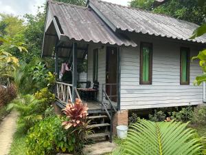 a small gray house with a porch and a staircase at Green Garden Bungalow Resort in Ban Khlong Kloi