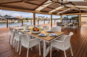 a wooden table with chairs and a bowl of fruit on a deck at Canal escape with private jetty and huge deck in South Yunderup