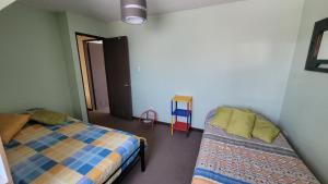 a bedroom with a bed and a chair in it at Acogedora Casa en Talca sector bicentenario 3 dormitorios 7 personas in Talca