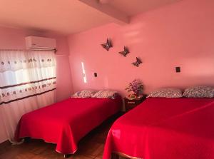 two beds in a room with pink walls at Hotel Ricarda Yopes Acapulco in Acapulco
