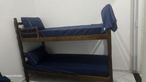 two bunk beds in a room with blue sheets at Cantinho dos netos-suites próximo ao Sesc em Bertioga in Bertioga