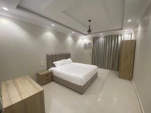 a white bedroom with a bed and a window at مساكن اركان in Quai