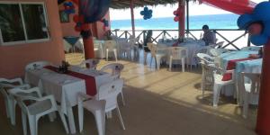 a restaurant with white tables and chairs and the ocean at Hotel Ricarda Yopes Acapulco in Acapulco