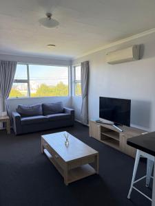 a living room with a couch and a flat screen tv at Delight On Dalton in Hokitika