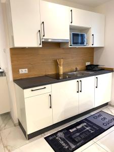 a white kitchen with a sink and a microwave at Kleine Auszeit in Friedrichshafen