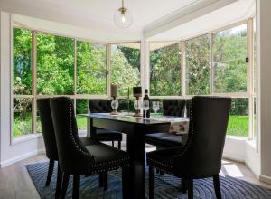 a dining room with a table and chairs and windows at Linden Getaway Bowral in Bowral