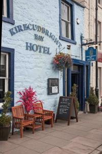 dois bancos sentados em frente a um hotel em The Kirkcudbright Bay Hotel em Kirkcudbright