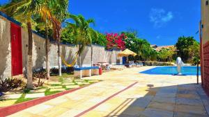 a resort with a swimming pool and palm trees and a person at Casa do Galego no Residência Família in Canoa Quebrada