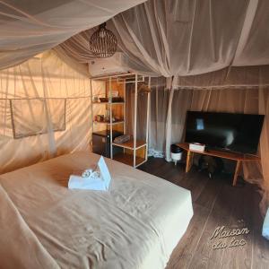 a bedroom with a bed and a tv in it at Maison Du Lac The Safari Tent in Wang Nam Khieo