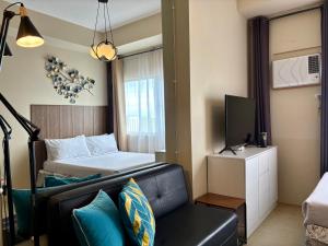 a bedroom with a bed and a couch and a television at A city escape at the Avida Towers Aspira 1 in Cagayan de Oro