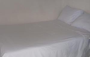 a white bed with white sheets and pillows at Habitaciones Casa Tinina in Boca Chica