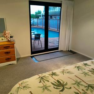 a bedroom with a bed and a view of a pool at One8Endeavour in Tauranga