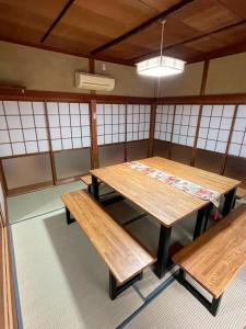 a room with two wooden tables and benches at やぎみちの家 yagimichi-noie in Sasebo