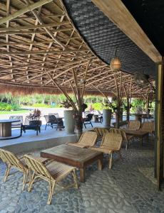 a patio with wooden tables and chairs under a roof at Lakwa Motel Lio Beach in El Nido
