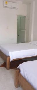 two beds in a room with a mirror at GTH Hostal in Arboletes