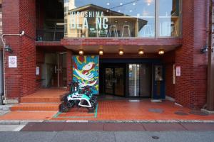 ein Motorrad, das vor einem Gebäude geparkt ist in der Unterkunft ゲストハウス ブランク Guest House BLANC in Hiroshima