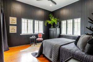 a bedroom with black walls and a bed and windows at Charming Queenslander surrounded by Rainforest in Port Douglas