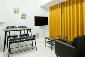 a living room with a yellow curtain and a table at CREST Nishijin by Tranova in Fukuoka