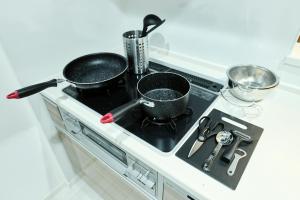 two pots and pans on a stove in a kitchen at CREST Nishijin by Tranova in Fukuoka