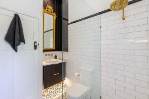 a white bathroom with a toilet and a sink at Charming Queenslander surrounded by Rainforest in Port Douglas