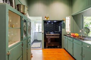 a kitchen with green cabinets and a stove at Charming Queenslander surrounded by Rainforest in Port Douglas +24 photos
