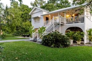 a white house with a balcony and a yard at Charming Queenslander surrounded by Rainforest in Port Douglas