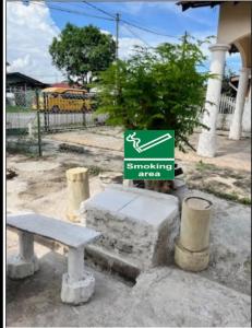 a sign for a smoking area with a bench at IMADUDDEEN Homestay in Kampong Bukit Kuang