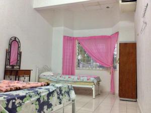 a room with two beds and a window with pink curtains at IMADUDDEEN Homestay in Kampong Bukit Kuang