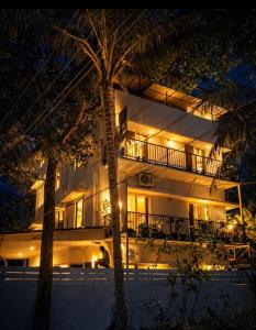 a hotel at night with palm trees in front of it at 88 villaggio Edappally in Edappally +31 photos