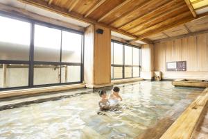 two children sitting in a swimming pool at Ooedo Onsen Monogatari Yamashiro Saichoraku in Kaga