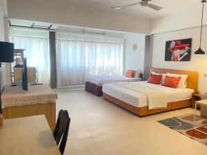 a hotel room with two beds and a table at A Day Rayong in Ban Pa Khan