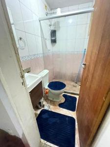 a bathroom with a toilet and a sink with blue rugs at Kitinete holl in Campos dos Goytacazes